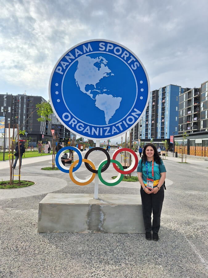 Untitled Eloisa Ojeda standing beside the logo of the Panamerican Games Santiago 2023